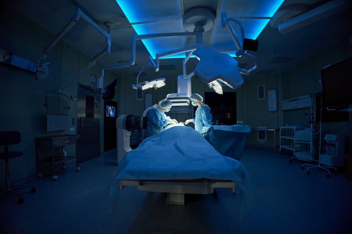 Wide angle shot of surgeons performing operation in hospital operating room, demonstrating advanced medical care and teamwork